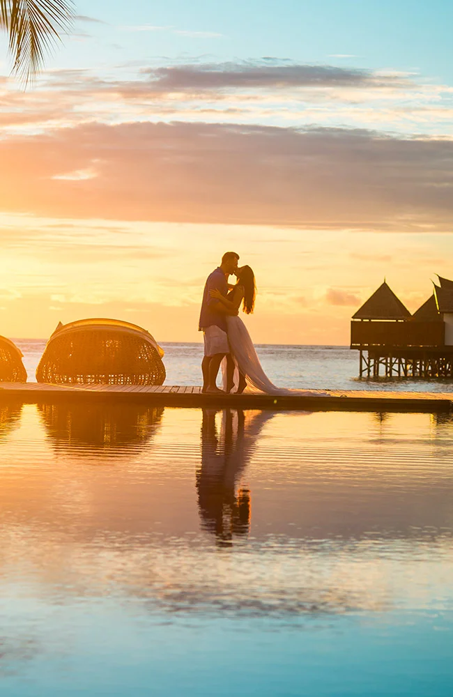 Couple s'embrassant sous un couché de soleil